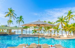 a resort swimming pool with chairs and palm trees at Barceló Ixtapa - All Inclusive in Ixtapa