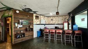 a bar with red bar stools in a restaurant at Curvão Surf House in Guarujá