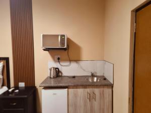 a kitchen with a sink and a tv on the wall at Masithandane lodge in Richards Bay
