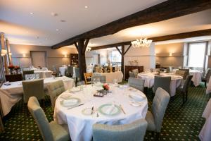 a dining room with white tables and chairs at Logis Hôtel Restaurant du Moulin in Ligneuville
