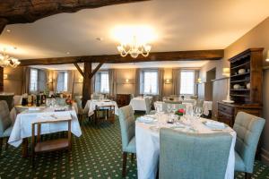 a restaurant with white tables and chairs and a chandelier at Logis Hôtel Restaurant du Moulin in Ligneuville