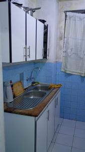 a kitchen with a sink and a blue tiled wall at Overport Two Bedroom Apartment in Durban