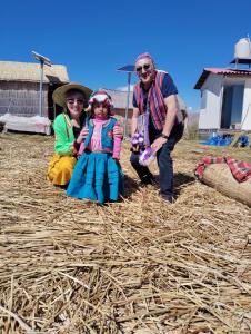 a couple of people and a little girl sitting on straw at Uros encantos del titikaka lodge in Puno
