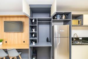 a kitchen with a stainless steel refrigerator and shelves at Studio Completo Perto de Tudo - MUV0410 in Curitiba