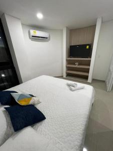 Un dormitorio con una cama blanca y un televisor. en casa fresh, en Rodadero