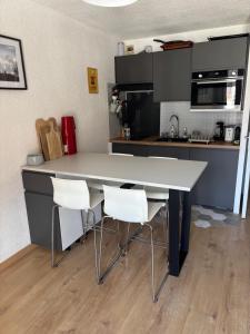 una cocina con una gran mesa blanca y sillas blancas en Location studio plein centre Les Carroz, en Les Carroz d'Araches