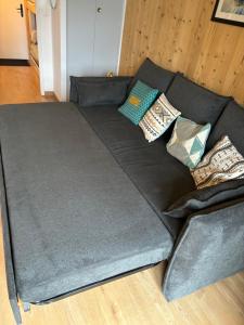 Un sofá negro con almohadas encima. en Location studio plein centre Les Carroz, en Les Carroz d'Araches
