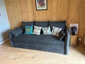 un sofá con muchas almohadas en una habitación en Location studio plein centre Les Carroz, en Les Carroz d'Araches