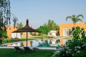 a pool with chairs and an umbrella next to a building at Domaine Bahi - Marrakech in Marrakesh