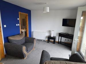 a living room with a couch and chairs and a tv at Burray Apartments - Tangles, Kelpie & Selkie in Burray Village