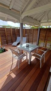 a table and two chairs on a wooden deck at TI-MANGO 1km de la plage communale quartier résidentiel in Sainte-Anne