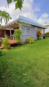 a house with a large yard with a porch at TI-MANGO 1km de la plage communale quartier résidentiel in Sainte-Anne