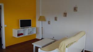 Habitación con cama y TV en una pared amarilla. en Orzola Para Descansar, en Orzola