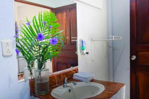 a bathroom with a sink and a vase with purple flowers at Cabinas Bahía Uvita - Marino Ballena National Park Lodge in Uvita