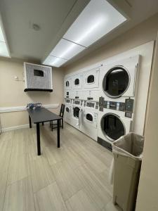 a laundry room with three washing machines and a table at Luxury Warehouse District Condo in Durham