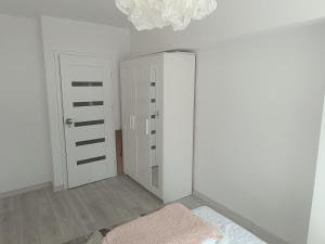 a white room with a door and a pink blanket at 2-room apartment, central & quiet in Gdynia