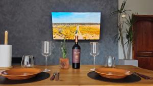 a wooden table with a bottle of wine and glasses at excelente calefacción, TV 55'' CON MUNDIAL 2026, Cochera, WIFI rapido, Colchón cómodo, Apartamento Gamán in San Luis