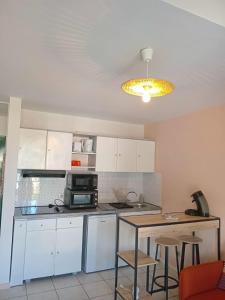 a kitchen with white cabinets and a table with a microwave at L'Ecrin - Duplex proche du CHU in Saint-Denis +8 photos