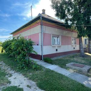 ein kleines rosa-weißes Haus mit einem Baum in der Unterkunft Boróka Vendégház in Püspökladány