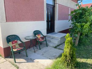 zwei Stühle und ein Tisch vor einem Gebäude in der Unterkunft Boróka Vendégház in Püspökladány + 3 Fotos