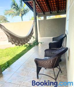 three chairs and a hammock on a porch with the beach at Casa Sol da Manhã - Piscina aquecida com hidromassagem - 300m da praia in Guaratuba