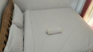 a white bed with a piece of paper on it at Savannah Apartments in Narok