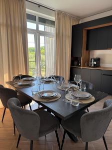 ein Esstisch mit Stühlen, Tellern und Weingläsern in der Unterkunft Agropensiunea TreiFrati 