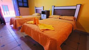 two beds in a room with yellow towels on them at Jazmin Hotel Boutique Colonial in Comitán de Domínguez
