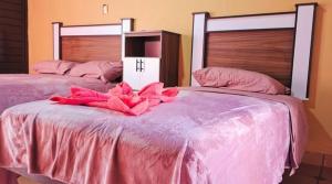 two beds with pink sheets and a pink flower on them at Jazmin Hotel Boutique Colonial in Comitán de Domínguez