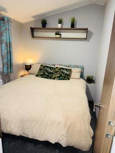 a bedroom with a white bed with plants on it at Vinchella-3 bedroom caravan in Grange Over Sands