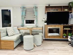 a living room with a couch and a table and a tv at Vinchella-3 bedroom caravan in Grange Over Sands