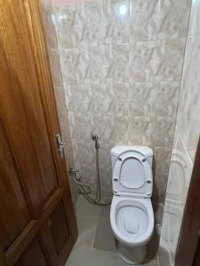 a bathroom with a toilet and a wooden door at Elzo Crib !!! in Dakar +4 photos