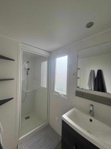 Un baño con ducha, lavabo y espejo. en Mobile home Camping Siblu Les Charmettes 4, en Les Mathes