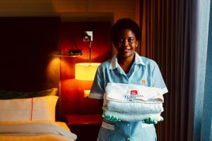 a woman holding a stack of towels in a hotel room at Turimar Business Hotel in Lobito