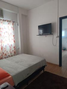 a bedroom with a bed and a flat screen tv at Kitnet Rústica Blumenau in Blumenau