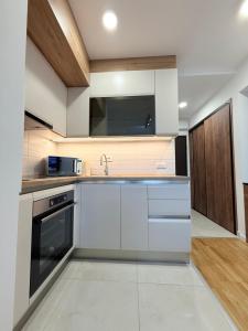 Una cocina con gabinetes blancos y un fregadero. en Apartment UNA, en Pančevo