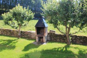 eine Steinmauer mit einem kleinen Gebäude neben zwei Bäumen in der Unterkunft Casa Rural Mikelenea in Lecároz