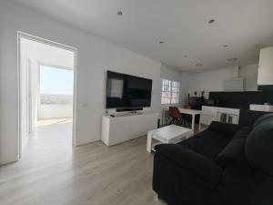 a living room with a black couch and a television at Apartamento con vistas al mar in Viladecáns