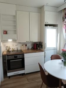 cocina con armarios blancos, mesa, mesa y mesa en Tilava kaksio Jussilankadulla, en Hyvinkää