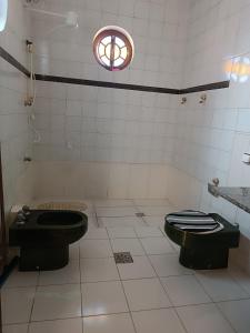 a bathroom with two black toilets and a window at Pouso Santo in Aparecida