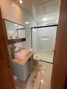 Un baño con lavabo y ducha de cristal. en Suíte Recanto Praia das Vieiras, en Porto Belo