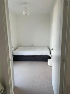 ein kleines Schlafzimmer mit einem Bett in einem weißen Zimmer in der Unterkunft Modern two-bedroom flat near Cambridge University Biomedical Campus in Trumpington