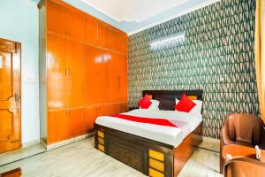 Un dormitorio con una cama con almohadas rojas. en Hotel O Royal Inn, en Faridabad