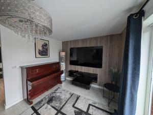 a living room with a piano and a flat screen tv at 14 Lumb close in Swindon