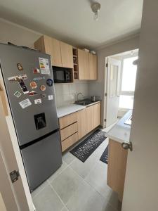 a kitchen with a stainless steel refrigerator and wooden cabinets at Departamento Temuco in Temuco