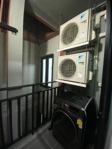 Ban Pra DokにあるCaesar's Suite Condo Koratのエアコン2台と電子レンジ付きのバルコニー