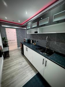a kitchen with white cabinets and a black counter top at Suite 1 Private Jacuzzi Spa Hot Tub & Sauna in Attercliffe