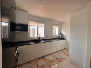 a kitchen with white cabinets and black counter tops at Ático con vistas al mar y terraza in La Alcaidesa