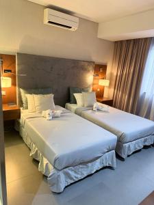 two beds in a hotel room next to a window at Turimar Business Hotel in Lobito +45 photos