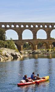 Un grupo de personas en una balsa en un río con un puente. en Le Cocoon Sernhac - chambre romantique, en Sernhac